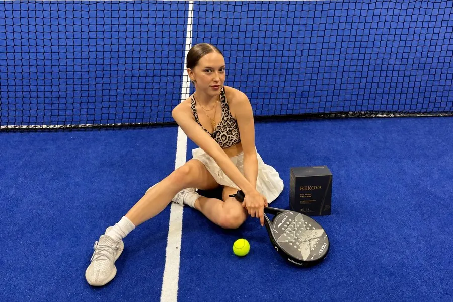 Padel player sitting on a blue court next to a Rekova box