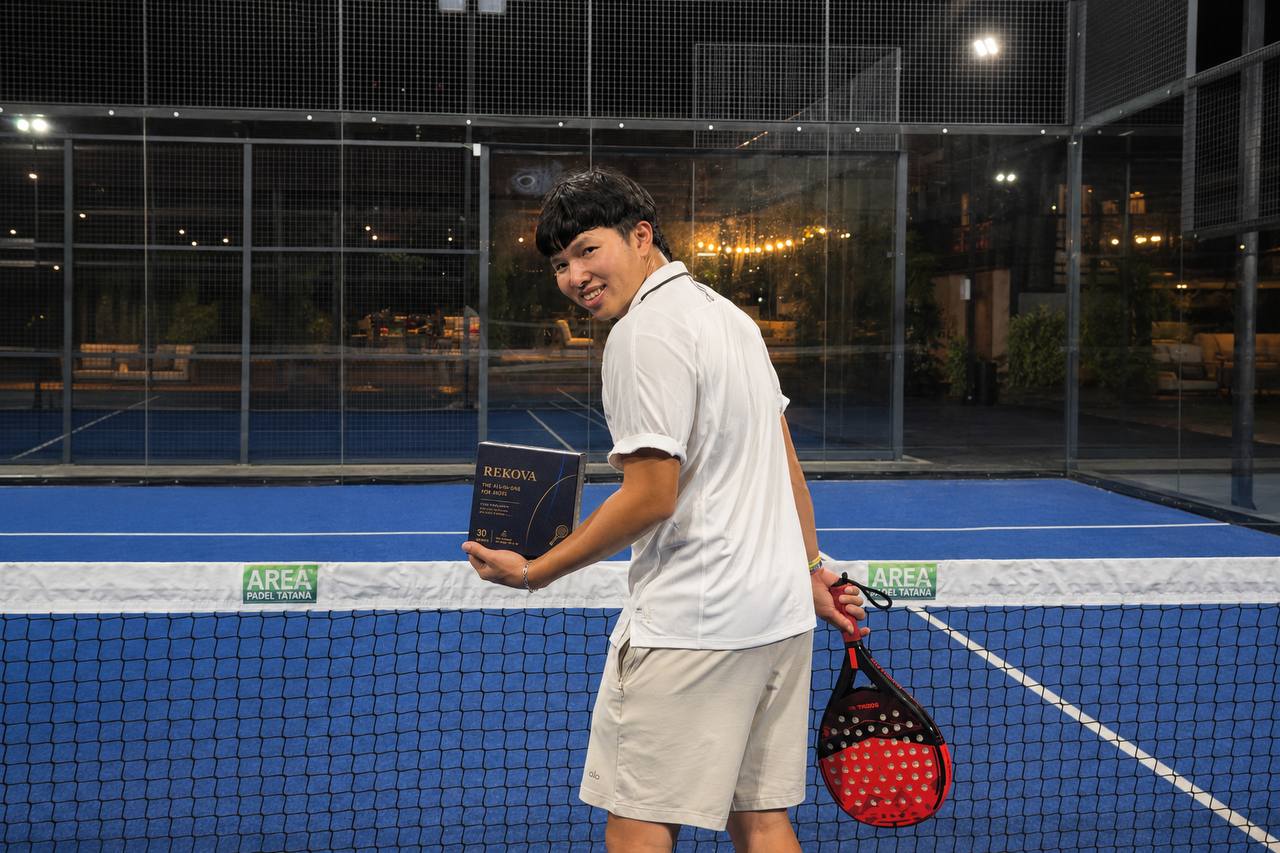 Padel player holding a Rekova box on a blue padel court