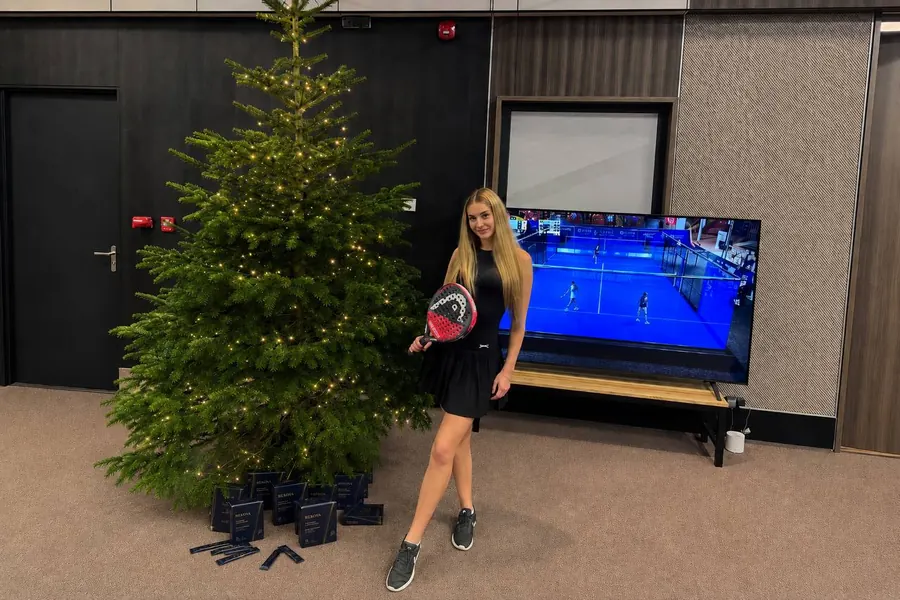 Padel player with a racket and Rekova boxes at an indoor court